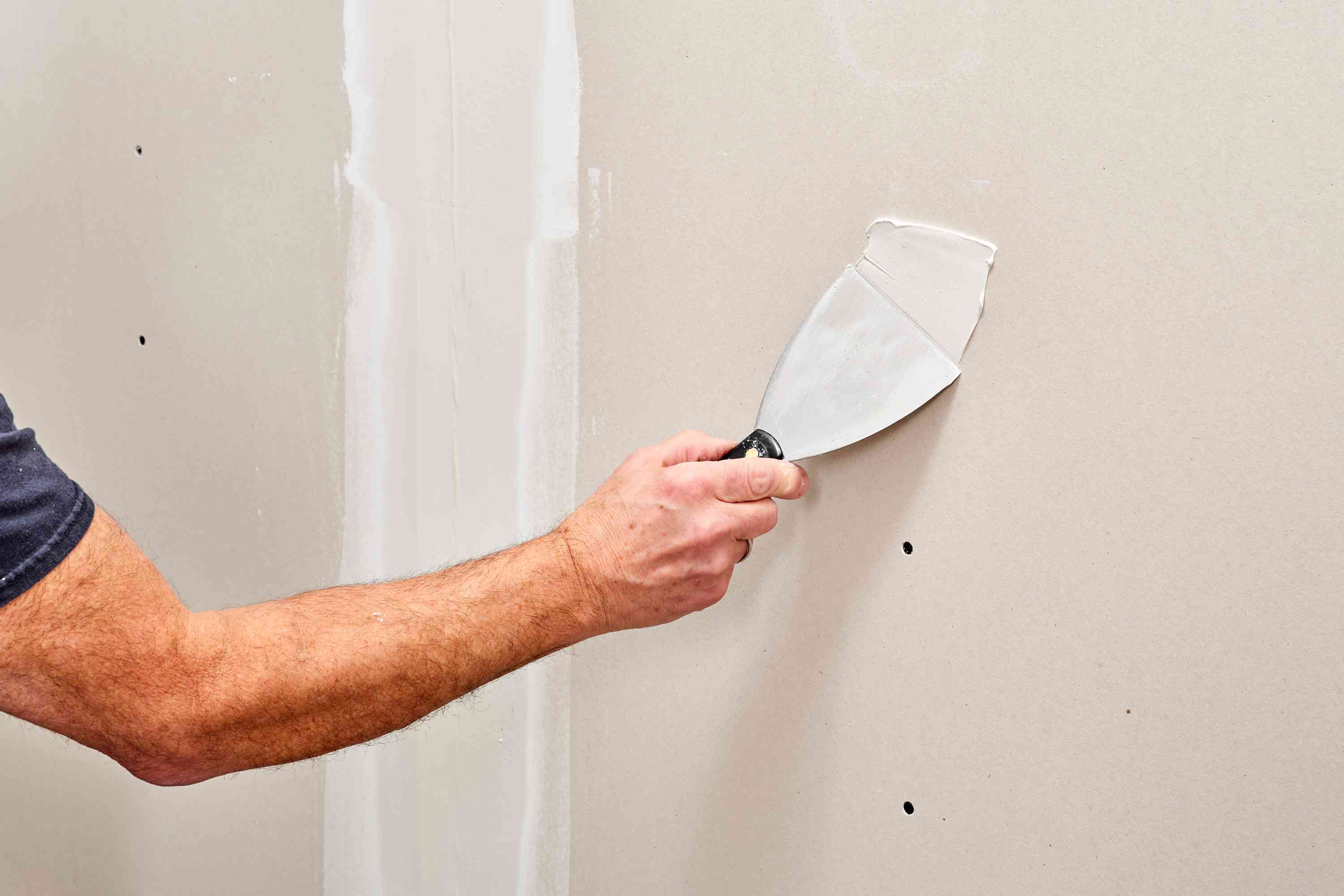 Skibo Services professional applying drywall paste to a drywall screw, ensuring seamless and flawless wall installation.